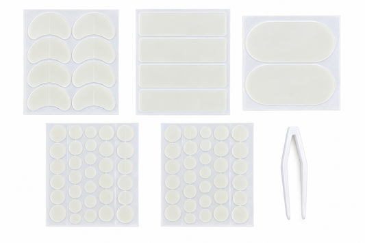 A set of white adhesive skin patches and a pair of white tweezers on a plain white background. The set includes crescent-shaped patches, rectangular patches, oval patches, round dot patches, and tweezers.